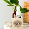 Palo Santo Protection Mist with a green leaves at the back 