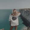 A girl facing the sea worn her Conscious Club T-Shirt