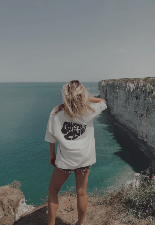 A girl facing the sea worn her Conscious Club T-Shirt