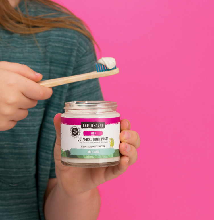 A girl holding the toothbrush with mild mint kids truthpaste